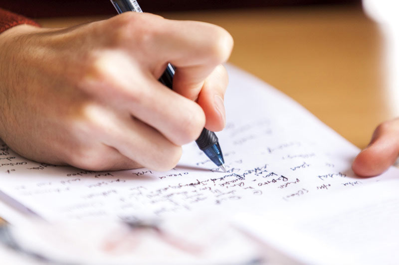 close up of a hand holding a pen and writing notes on a page