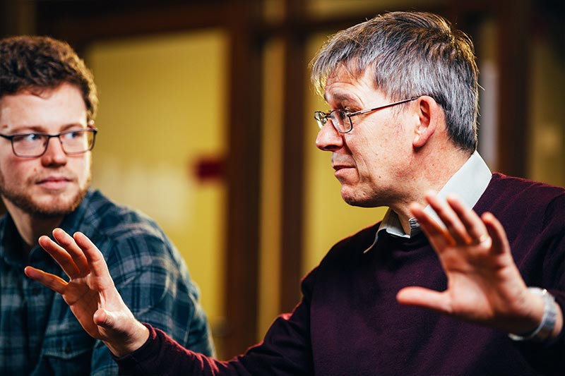 an academic explaining something to a postgraduate student in the breakout area of the graduate school