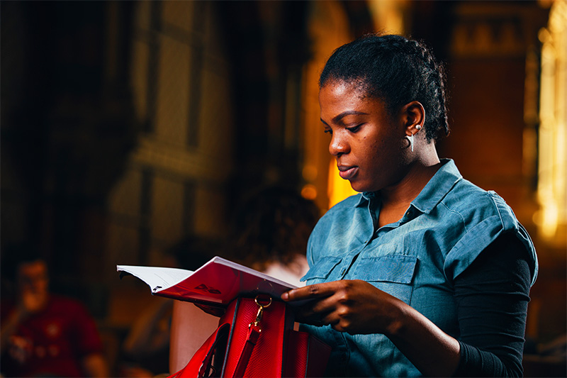 female leaning her notebook on red handbag and reading notes