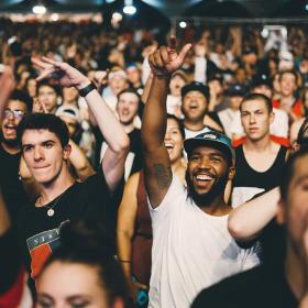 Two men in a crowded concert raising their hands