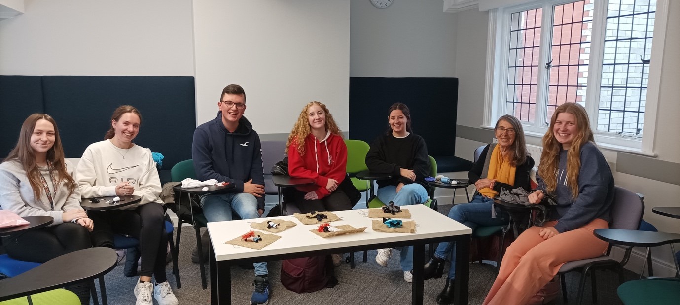 Students at the workshop sitting behind a table containing various textiles