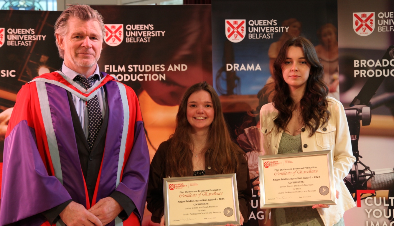 man in academic gowns standing with two students who are holding certicates