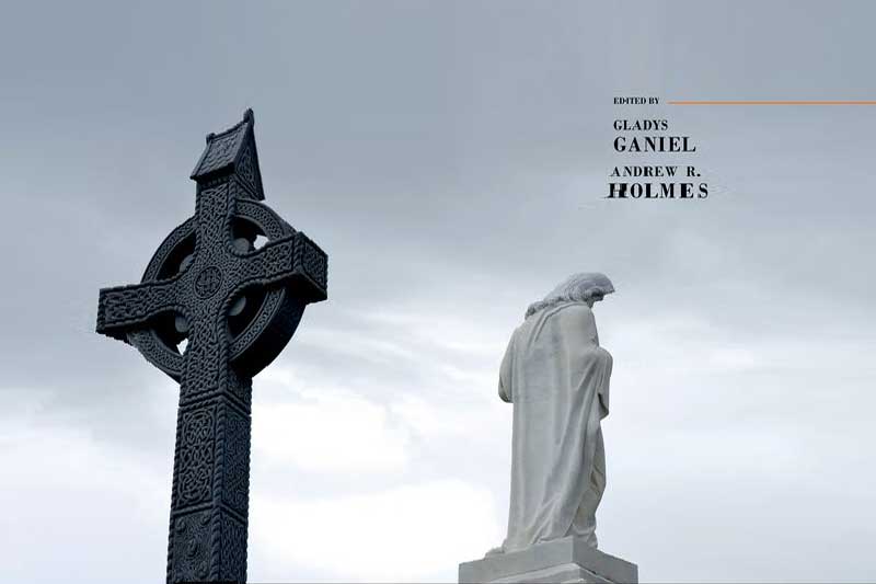 A celtic cross and statue against a grey sky