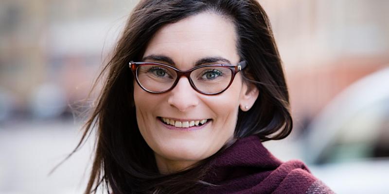 headshot of woman with mid-length datk hair, wearing glasses and smiling