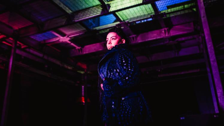 person standing looking off camera inside a dark studio with lights in the background