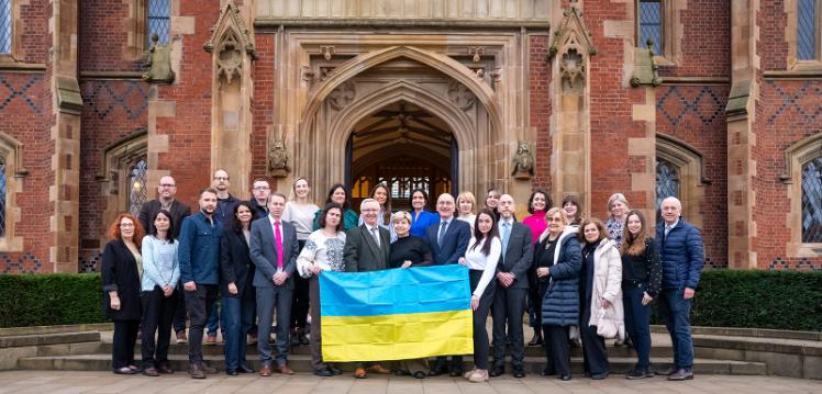 a group of people holding the Ukrainian flag in front of a red brick building