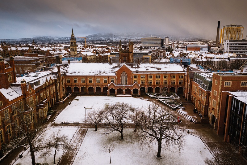 Queen's University building covered in snow, creating a picturesque winter scene with a serene, peaceful atmosphere.