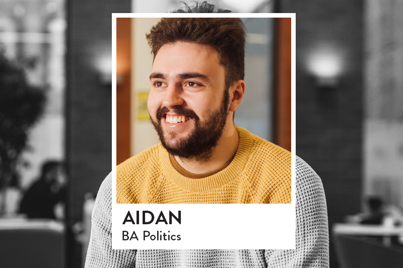 Student sitting in Junction smiling with yellow jumper looking forward