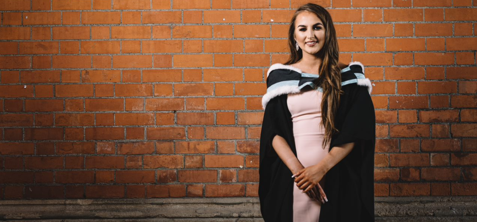 female student who has just graduated standing with degree certificate