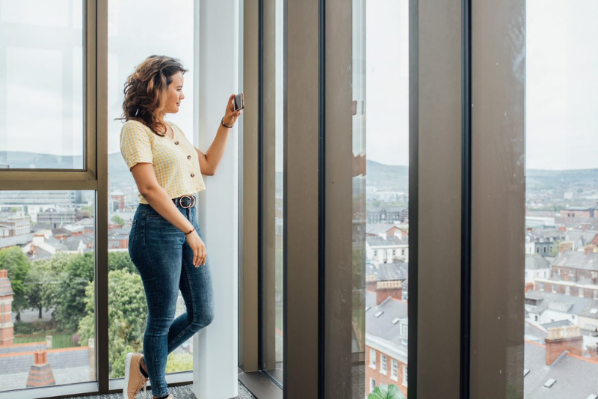 female student taking a photo of a view from a top floor office