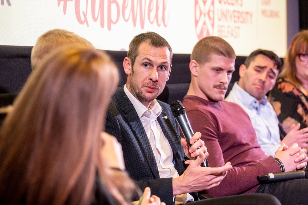 Dr Michael McKillop MBE speaking on stage at the Mental Health Awareness Week 2023 panel discussion in the QFT