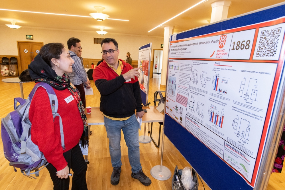 two postdocs discussing an academic poster at the poster presentation at Queen's Postdoc Showcase 2023