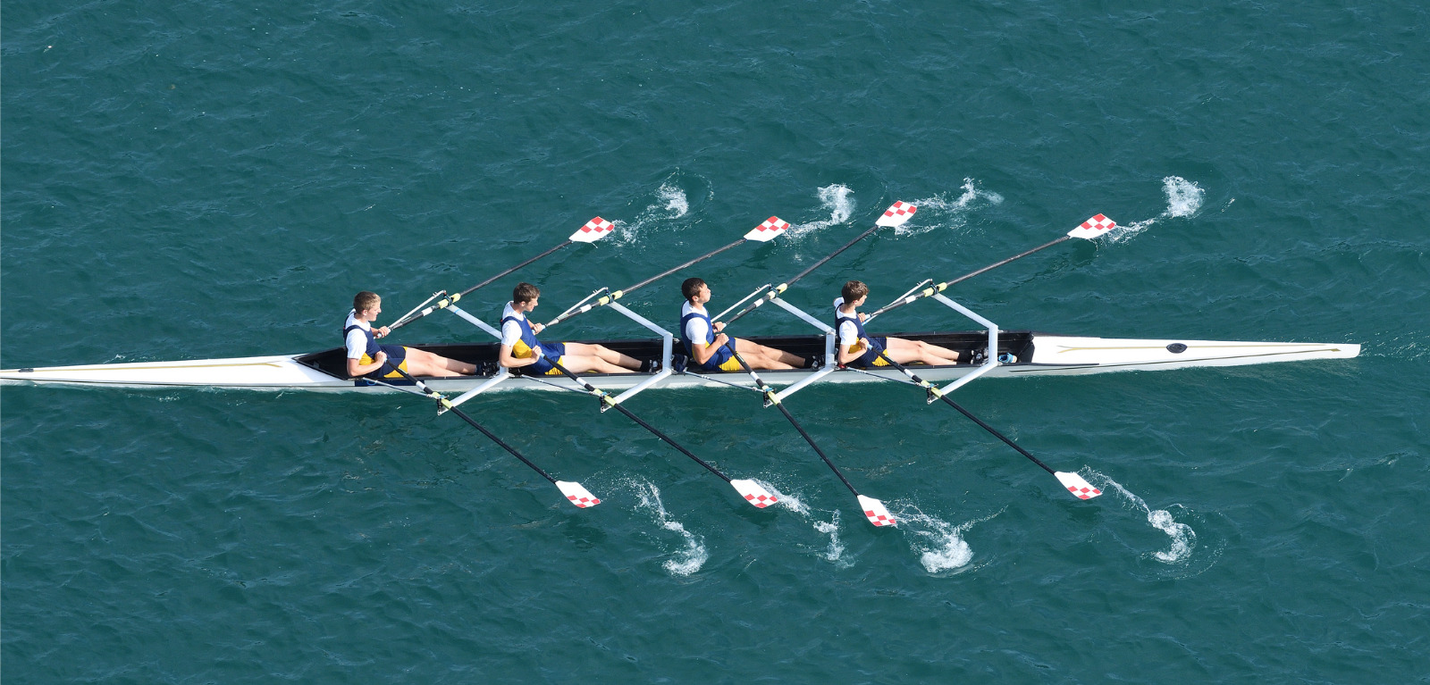 Four men in a boat co-operating