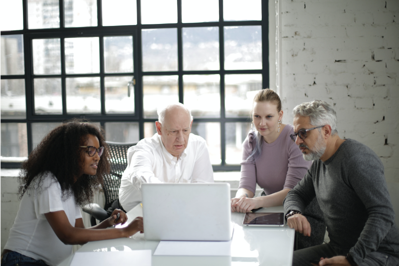 Four persons discuss around a laptop