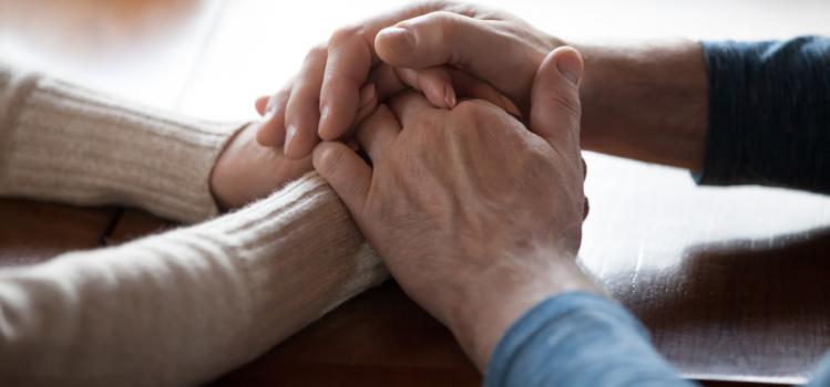 man holding woman's hands across a table