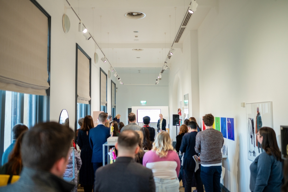 full gallery view of event attendees listening to a short talk at the launch of Queen's new Staff Network for Promoting Linguistic Diversity and Minority Languages, in the Naughton Gallery