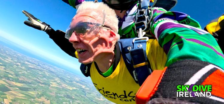close-up looking towards the sky of a man skydiving out of a plane with Skydive Ireland logo over the image