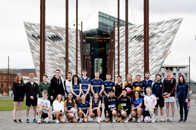 group of young people in sports gear posing for a photo outside the Titanic Centre building, Belfast